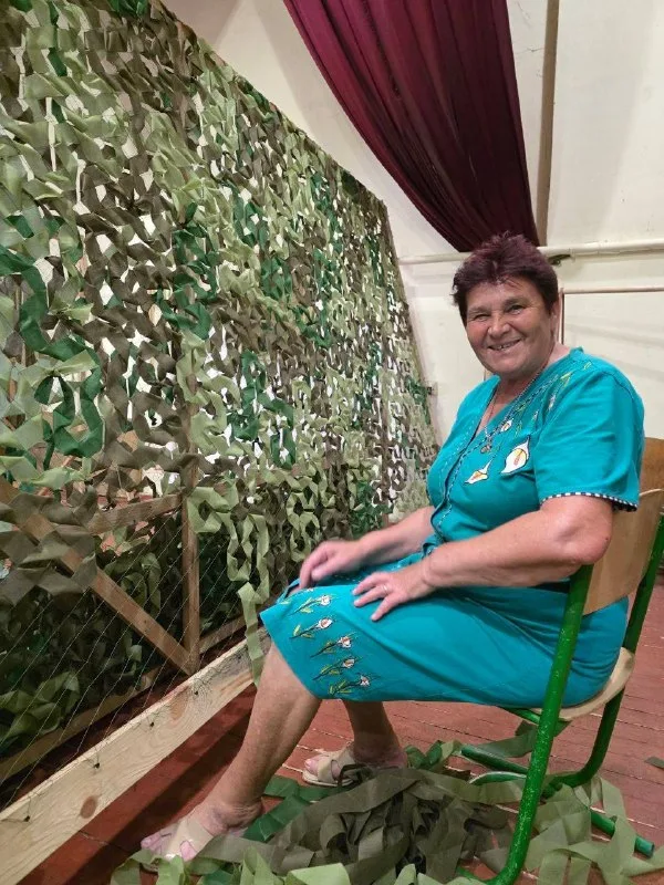 A volunteer of the "Together to Victory" group beside a finished camouflage net in Zdvyzhivka. Photo: Bucha City Council