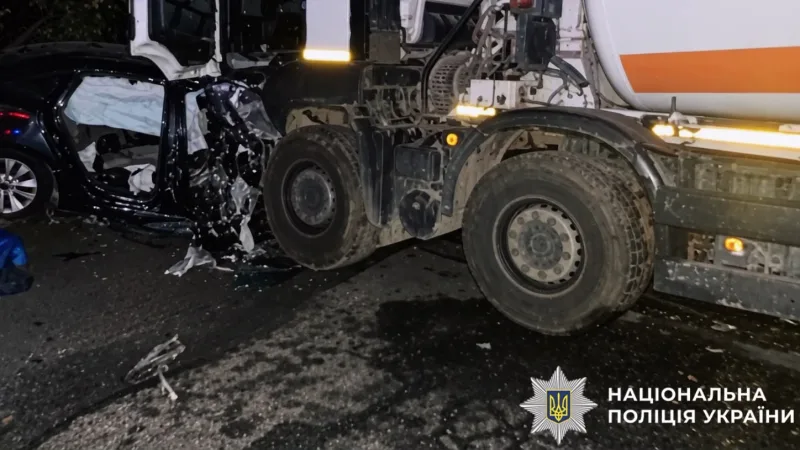 The damaged Dodge Dart beside the concrete mixer at the scene