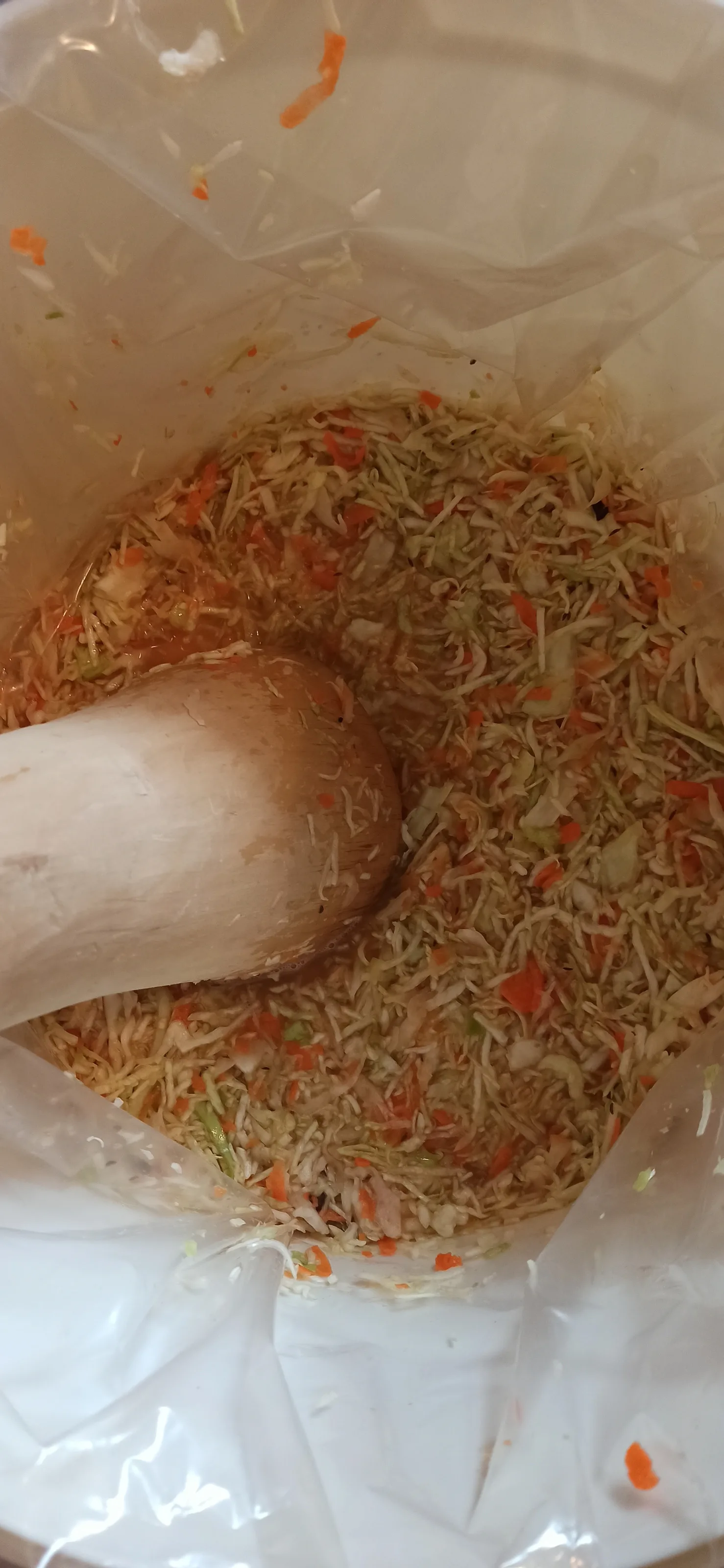 Packing the cabbage down in the bag with a wooden pestle