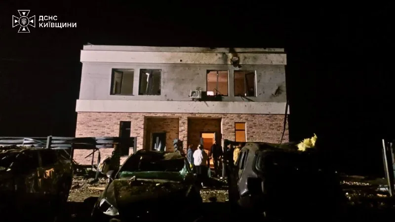 A damaged house and wrecked cars next to it