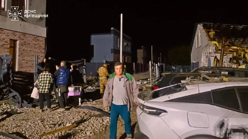 Residents next to damaged houses and cars