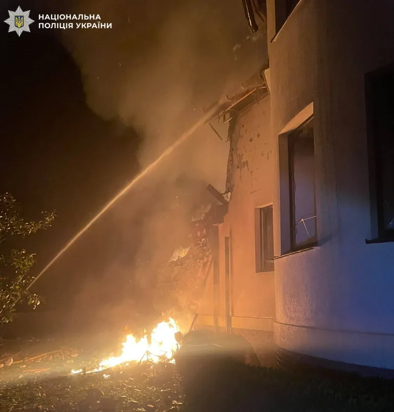 Гасіння пожежі біля пошкодженого будинку вночі