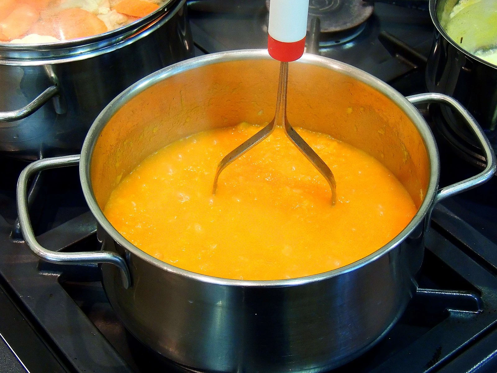 The soft pumpkin is mashed with a masher