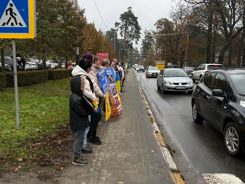 Учасники акції з банерами на тротуарі вздовж Варшавської траси